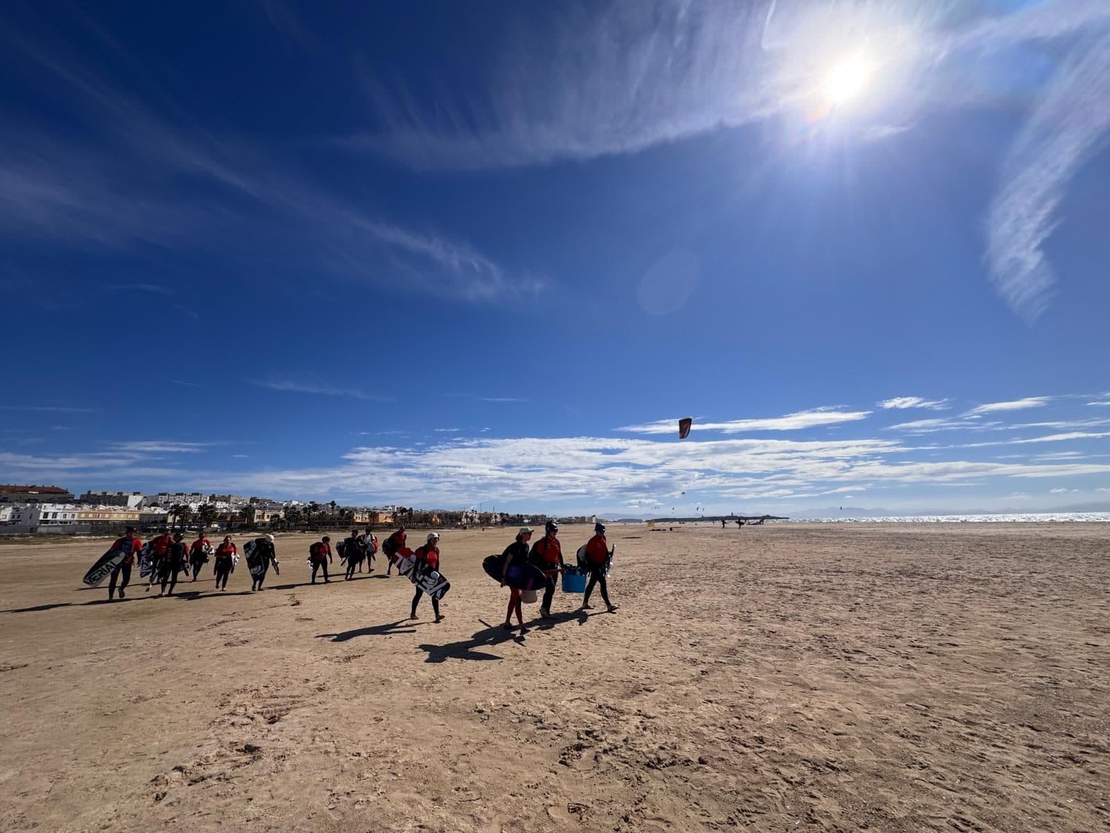 Die Kitegruppe trägt ihre Boards über den weiten Strand